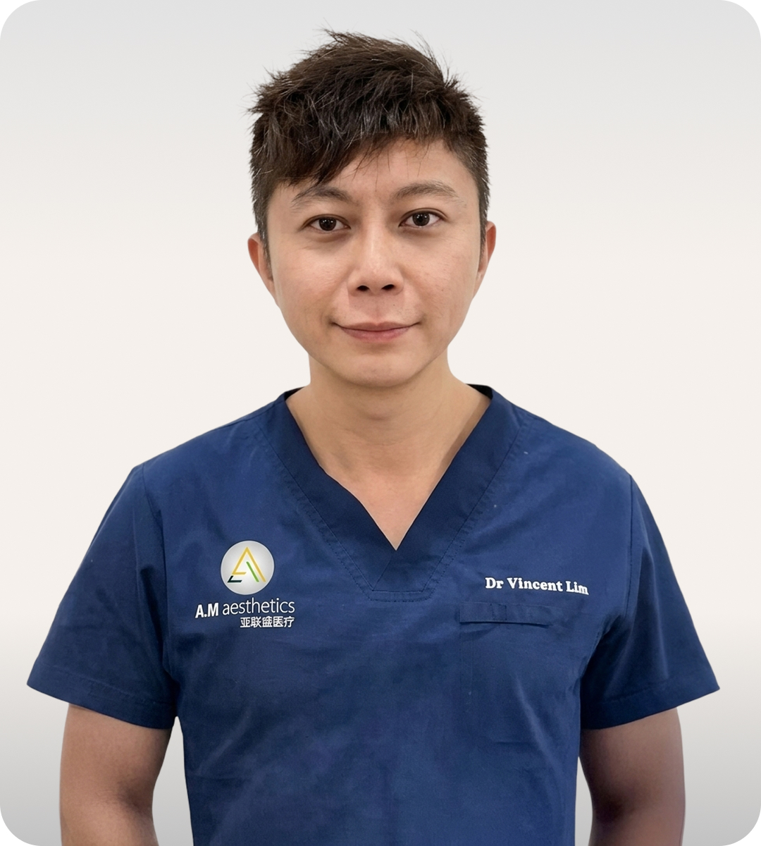 An aesthetic doctor wearing a navy scrub shirt with the A.M aesthetics logo.