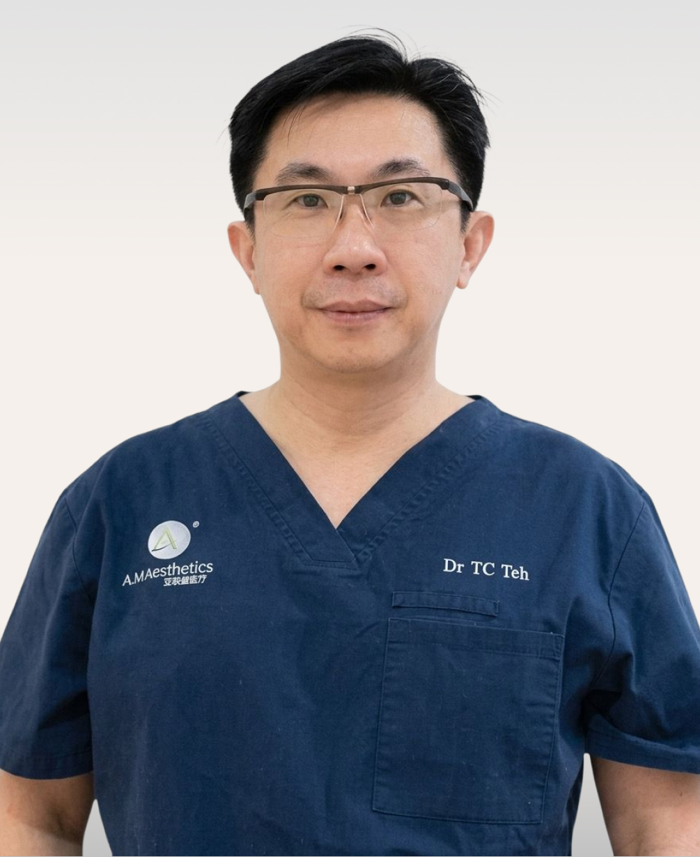 A medical professional wearing blue scrubs with glasses, posing for a portrait.