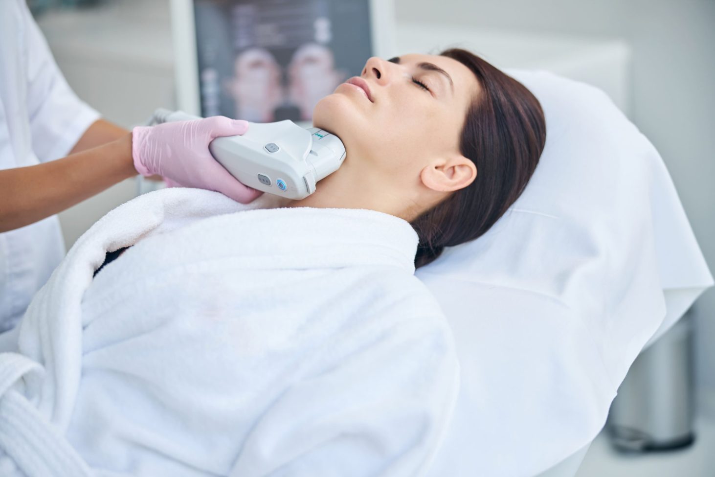 A woman receiving an aesthetic skin treatment while lying on a treatment bed.