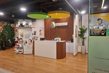 The reception area of AM Aesthetic SG featuring a modern design with green and yellow ceiling lights, wooden panels, and product displays.