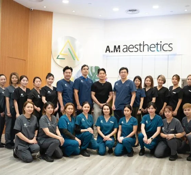 A group photo of the staff from AM Aesthetic SG, smiling in their clinic.