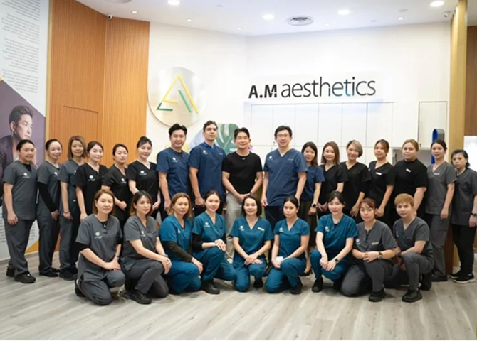 A group photo of the staff at A.M. Aesthetics, showcasing team members in clinical attire standing together in a modern clinic setting.