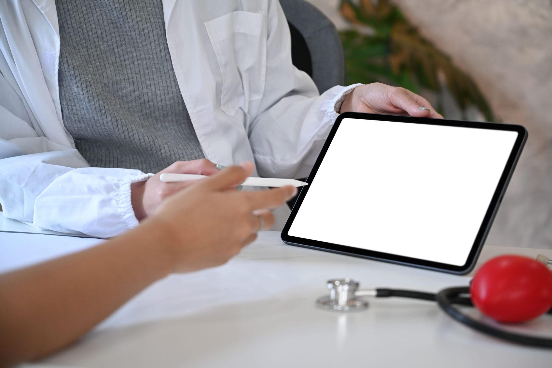 A healthcare professional holding a digital tablet while discussing something with a patient.
