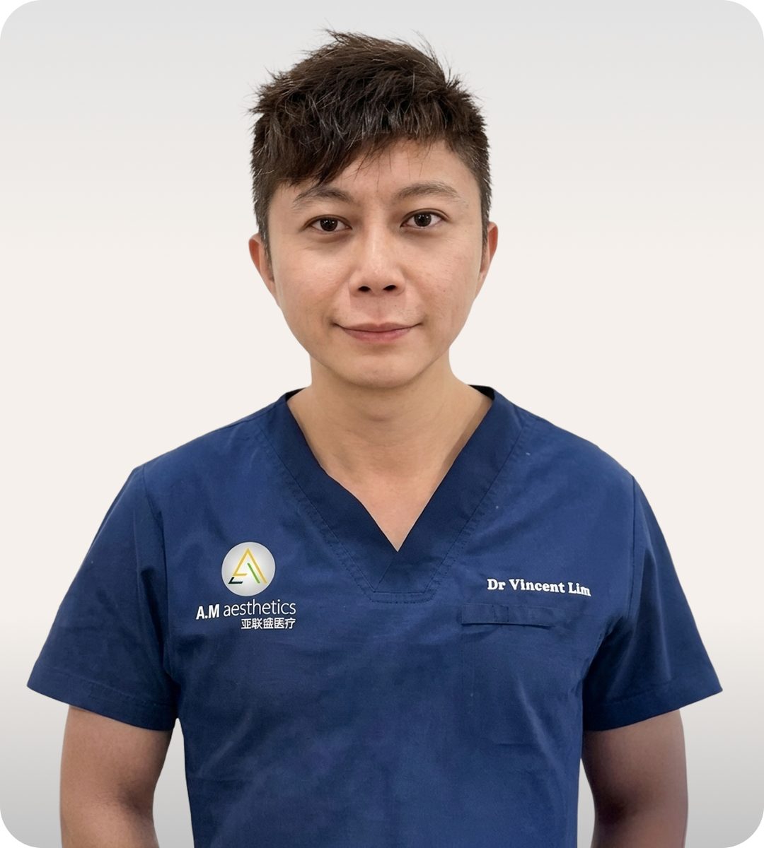 An aesthetic doctor wearing a navy scrub shirt with the A.M aesthetics logo.