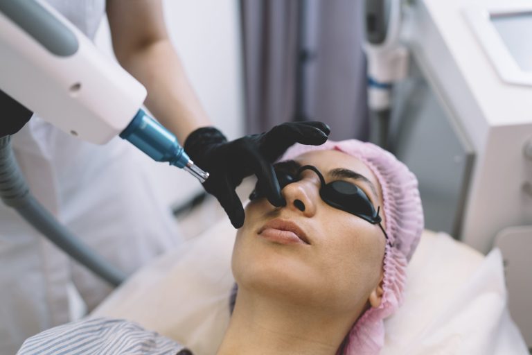 A woman receiving a modern laser treatment at a beauty clinic while wearing protective eyewear.