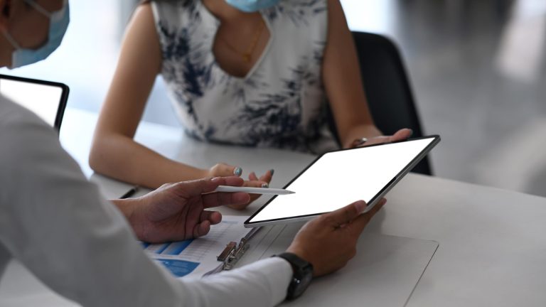 Two business professionals discussing charts and data using a digital tablet during a meeting.