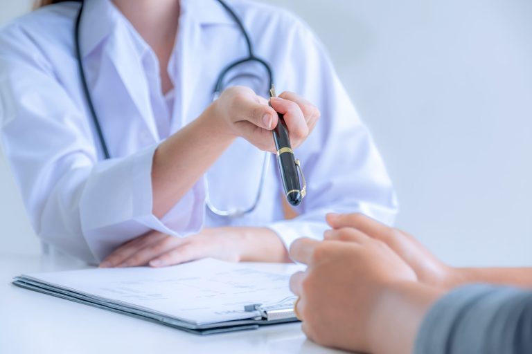 A doctor handing a pen to a patient for signing documents during a consultation.