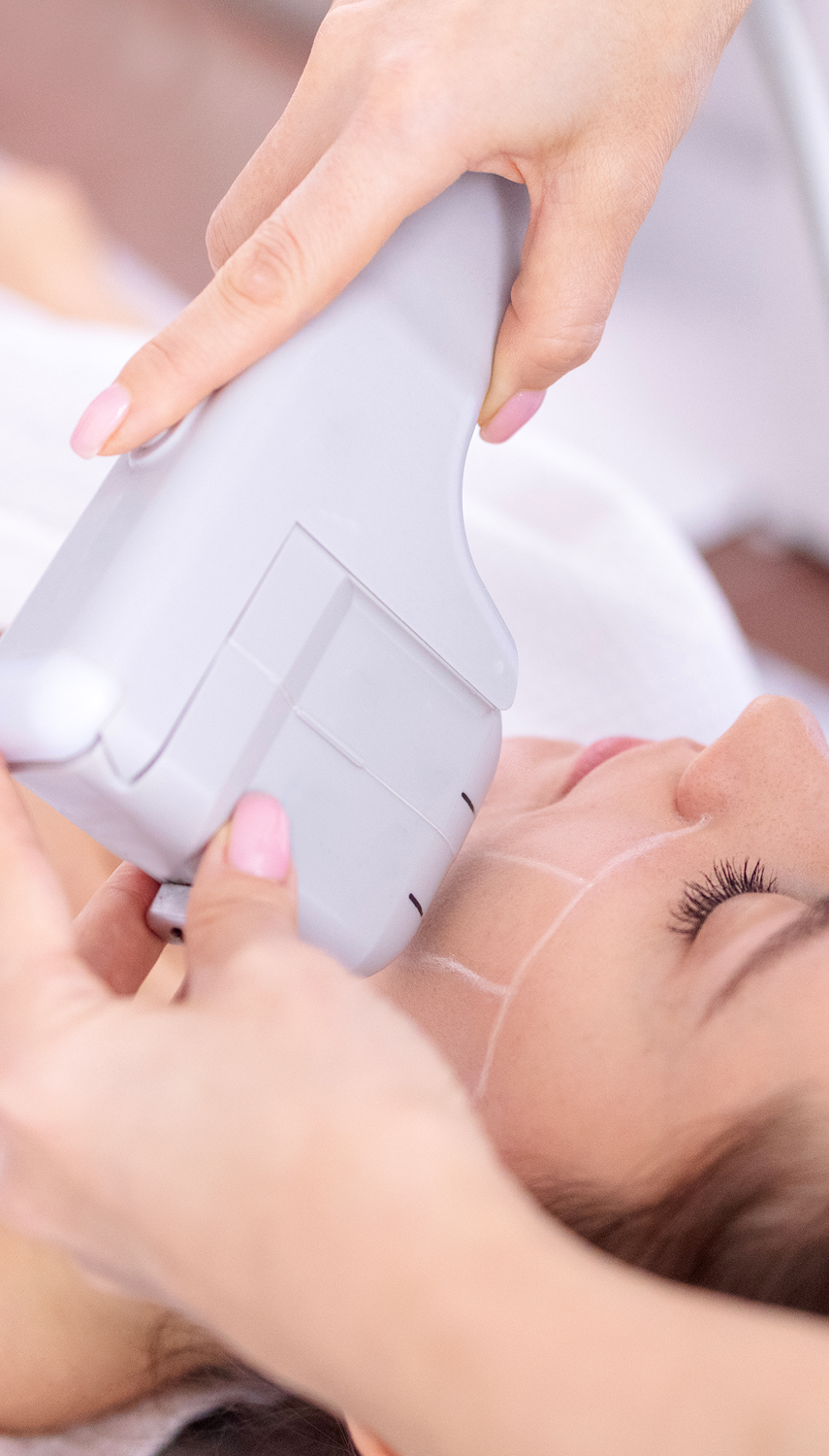 A woman receiving a facial skin treatment at a spa, with a device applied to her face.