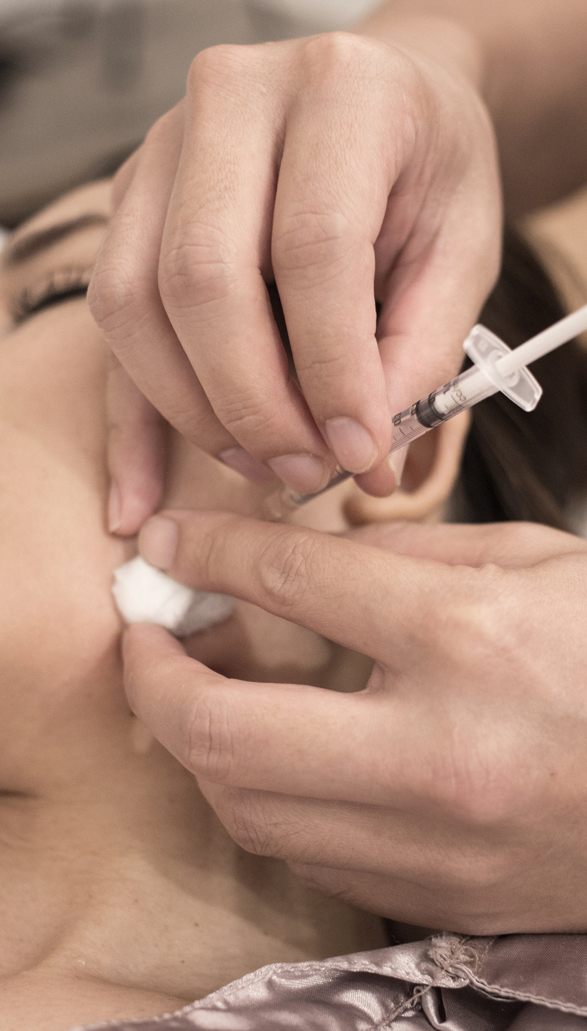 A close-up view of a person receiving a cosmetic medicine injection with a syringe.