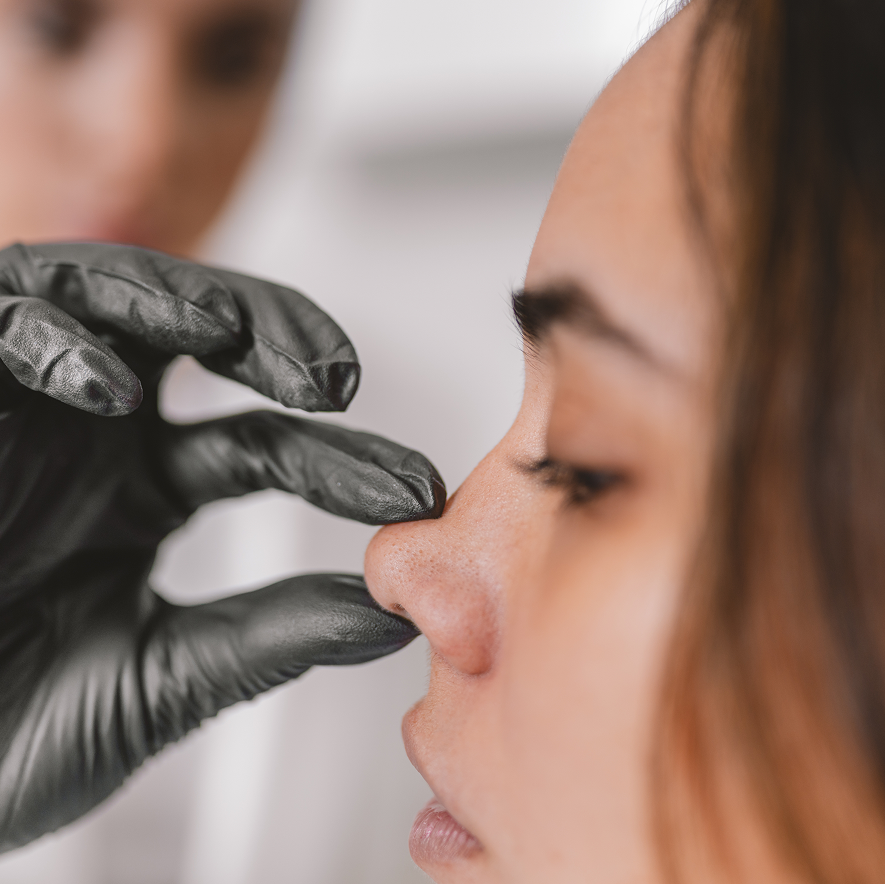 A close-up of a gloved hand preparing for a cosmetic procedure in a clinic setting.
